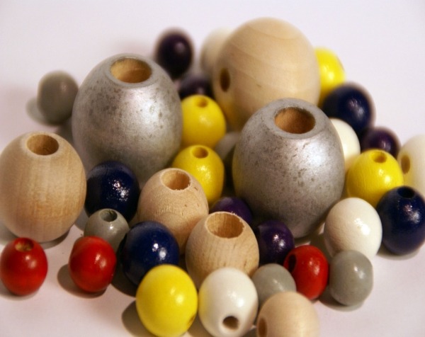 Assorted painted and unfinished wooden beads with drilled center holes, available in bulk for large-scale production.